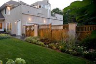 A Craftsman-style cedar fence with a bordering garden provides an eye-catching complement to this natural landscape. Peek-a-boo diamond-shaped windows on the gate allow for a little look-see into the yard beyond.