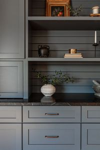 Blue-grey built in kitchen cabients, dark coutner top, and horizontal shiplap