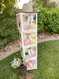 A little cowgirl in on her way baby shower theme decortations. BABY boxes filled with ballons.