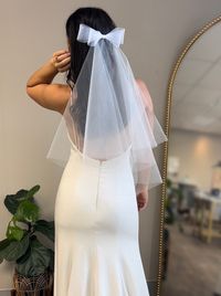 This double layer tulle veil with a horsehair bow is a whimsical and feminine wedding day look! Lightweight tulle fabric drapes beautifully from the comb down to a more voluminous shape on the bottom. The veil is completed with a horsehair double bow which gives the bow structure and a perfect bow shape! Lengths: -Shoulder (24 inches) Pictured* -Elbow (30 inches) -Fingertip (38 inches) -Waltz (58 inches) -Chapel (90 inches) -Cathedral (110 inche) This is a raw edge veil made with tulle fabric. M