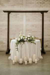 This sweetheart table is decorated with a lush floral arrangement featuring white roses, baby's breath, queen anne's lace, eucalyptus, and italian ruscus. Floral design by Imogen Floral Design.