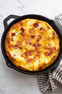 Puffy keto frittata in a cast iron skillet with a striped napkin.