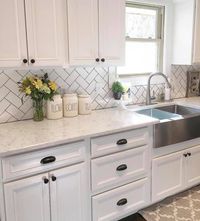 White kitchen cabinets with white counters and black hardware.