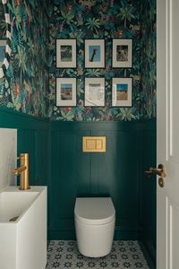 A formerly dark secondary living area was carved up to provide useful support spaces: a small toilet room, utility room, and a walk-in pantry, with the leftover space given back to the living room. Rich green wallpaper and brass fittings create a sophisticated, luxurious feel to the downstairs toilet. Location: Putney, Wandsworth. Architecture: Rider Stirland Architects Photograph by Chris Wharton. Green toilet room | Wall panelling | Wallpaper green | Green decor | Dark green bathroom