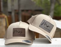 Embrace your newlywed status with pride, as our meticulously crafted hats bear charming Mr. and Mrs. patches. These elegant leatherette patches offer the look and feel of genuine leather without using animal products. Price is per hat. If you need two hats, please add two items to your cart.   Grab a pair of these gorgeous personalized couple hats now and elevate your moments with your loved one to a whole new level of fabulousness. Get ready to dazzle on your honeymoon, make unforgettable memor