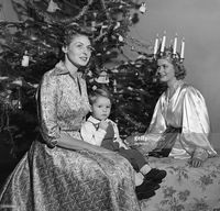 Sweden's 'Light Queen,' Kerstin Ornoe with Ingrid Bergman and her son, three-year-old Robertino. Ingrid, who is married to movie director Roberto Rossellini, had the 'Queen' as a special guest at a Christmas Party. The Light Queen was in Italy to attend official 'Lucia' festivals.