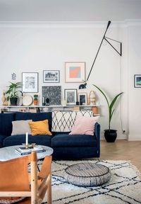 Amazing wall art gallery, full of color. Dark blue couch, perfectly patterned rug and floor cushion.