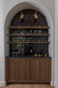 Custom dry bar with dark purple Zellige tile, with brass fixtures and hardware. Walnut cabinetry with reeded front detail.