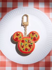 Bring a slice of Disney magic anywhere you go with the Mickey Mouse Disney Pizza Bag Charm. Mickey Mouse’s signature silhouette takes a cheesy pizza form with this accessory, adding playful personality to any look. Perfect for pizza addicts and Disney fans alike, easily clip this bag charm onto any purse, backpack, or tote. Enhance your bag with our stylish Bag Charms crafted from premium materials. Please consider your bag's material to prevent potential surface impact. Enjoy accessorizing with