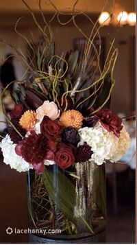 Autumn or fall centerpiece with Burgundy and pink roses, dahlias, branches, feathers, and white hydrangea