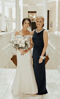 Mother of the bride in navy gown with jewel encrusted neckline standing beside bride