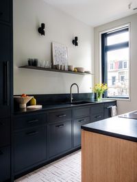 The kitchen counters and integrated sink are honed, locally quarried soapstone. The cabinetry was painted blue-black to match, and the island is a contrasting white oak. The white zellige floors were laid in a pattern referential to the parquet flooring in the living room. The breakfast area includes a built-in bench made from the same white oak as the island and a custom table designed for the space. New doors with transom windows were added, leading to a new steel deck in the rear yard.