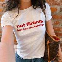 "Not Flirting Just Hot And Talking" Graphic Slogan Printed On Aesthetic Retro Vintage 90s Y2k Baby Tee Shirt with our own unique font.  🎨 Available in White, Light Pink, Light Blue, Navy, Black. If you need a different color, please let us know! (Ash, Red, Sport Grey & Green)  🎁 Our baby tees are perfect gift for her or him offering timeless fashion and versatility that anyone will cherish. Baby tees, popular in the '90s, have short sleeves and a slightly cropped body, giving a flattering femi