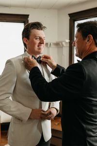 Groom getting ready with his dad on his wedding day. Dad adjusting grooms wedding tie.