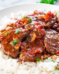 This Easy Swiss Steak recipe is made with inexpensive beef, cooked down until tender in a flavorful tomato sauce. Made all in one pot, an impressive steak dinner doesn't have to cost you so much money and effort! #swisssteak #recipe