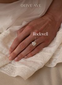 14K Yellow Gold | Rockwell features a bold emerald shaped center stone with two pear accent stones on each side. Set in a tulip three stone basket on a pinch tapered half round shank.