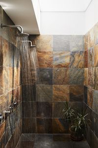 Covered in slate squares from Cambridge Tile, the master bathroom includes a double shower  with rain heads by M&Z Rubinetterie. A skylight lets in natural light while maintaining the residents’ privacy.