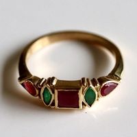 A garnet center is flanked by contrasting emerald and delicate blossoms of rubies. Unforgettable charm.