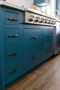 Blue kitchen cabinets. LVP flooring. Stunning brass pendants. White quartz coutnertop.