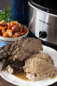 The tender pork roast of your dreams: As easy as it is delicious, and cooked hands-off in the slow cooker with potatoes, carrots and gravy!  #slowcookerrecipes #crockpot #porkrecipes #porkroast #roastdinner via @cookthestory