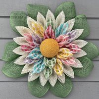 This cheery little front door wreath is sure to add the perfect finishing touch to your springtime or Easter decor and would make a perfect Mother's Day or baby shower gift.  Its petals are crafted from poly burlap mesh in a solid shade of cream as well windowpane mesh in pastel tones. The flower center is made from glittery yellow cording.  Lime green leaves peak out from the back.  Measurements are approximately 21" in diameter, including the green leaves, and 4" deep so it would fit perfectly