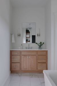 Spa experience at home. Light wood vanity. Sconces. Soaking tub.