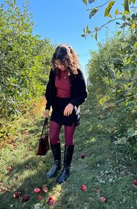 Needing some apple picking outfit inspiration? This burgundy outfit is so cute and perfect for fall. Pair knee high boots with burgundy tights, a black mini skirt, a burgundy t-shirt, and a black cardigan.