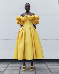 An off-the shoulder corset dress with an exploded neckline and sleeves and bone detailing in pop yellow poly faille. From the Alexander McQueen Pre-Autumn/Winter 2022 collection by Sarah Burton. Photographed by Philip White.