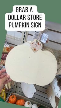 Grab a dollar store wood pumpkin door hanger and embellish it with peel-and-stick wallpaper, a birch stick, and simple raffia bow.