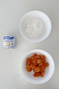 Ingredients to make Apricot and Coconut Balls on a speckled bench.