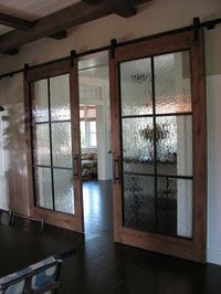 Industrial chic barn style sliding doors with rippled glass panes allow privacy but still allow light to filter through.