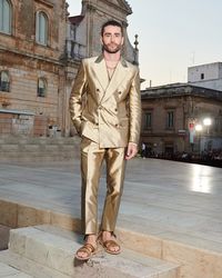 Pelayo Diaz wore a double-breasted Sicilia-fit suit in gold silk Mikado, styled with a see-through tulle top. He completed the look with sandals of rope fastenings and a yellow gold curved necklace composed of 46 different gemstones with different cuts and settings.