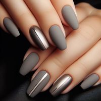 A sleek and modern design with nails painted in a soft, matte grey. The matte finish gives the nails a smooth, velvety texture. Accent nails are adorned with a single metallic silver stripe down the center, creating a chic and minimalist look. The combination of matte and metallic finishes adds depth and contrast to the design.