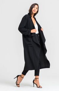 Be a fashionable one with the Sandra Black Waterfall Trench Coat by Lush Cothing! Black medium-weight woven fabric shapes a collared, draping front with square pockets. Oversized long sleeve bodice tapers slightly cuffed sleeves.k