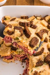 Reuben Casserole is a tasty dish loaded with cubes of rye bread, sliced corned beef, sauerkraut, dill pickles, Swiss cheese and Thousand Island dressing.