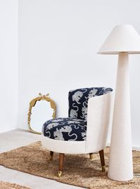 A statement conversational piece, the Ola chair has been updated with our new Tigris tiger print, designed in the OB studios. The classic tub silhouette combines a textured blue print with a linen-like neutral fabric, wooden legs and golden feet.