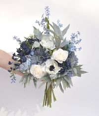 CONGRATULATIONS on your upcoming wedding! This beautiful silk flower bridal bouquet is boho-inspired, with a stunning mix of white roses with blue wisteria and other faux/artificial flowers. Gorgeous eucalyptus greenery completes the look and all stems are flawlessly wrapped in ribbon of your color choice!