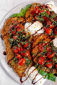 This chicken caprese recipe is packed with flavor and is sure to please everyone at the table! The chicken cutlets are breaded with Italian breadcrumbs and pan-fried until crispy and golden brown. Then, they are topped with garlic-roasted tomatoes, creamy burrata cheese, fresh basil leaves, and a drizzle of balsamic glaze. So easy to make and totally delicious!