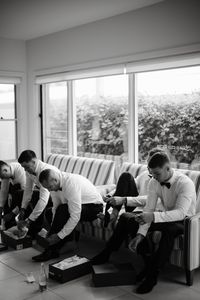 Black and white wedding photography by Calla Lily Collective.  The Groom and his Groomsmen get ready for the big day with a beverage in hand. Dressed in sleek white button downs and classy bow ties.  Contact us to learn more.  See you soon,  Calla Lily Collective x  #weddingphotography #blackandwhite #brideandgroom #groomsmen #groom