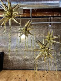 A collection of 4 starbursts with tinsel tails, cute on their own or paired with any of our NYE decor! Air filled, will last weeks indoors.