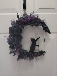 Cat moon wreath. Purple and black moon wreath. Black cat wall decor. Halloween door decor. Crystal moon wreath. Witchy wall art. Gothic gift This unique handmade moon wreath is perfect for all year round. Give as a gift to someone who loves Halloween, witchy, and gothic thing. Hang this on you door or wall for that Halloween vibe. Made with grapevine shaped into a moon shape then painted black. Used black faux floral and dried purple baby's breath. Amethyst crystal is real. Black cat is wooden a