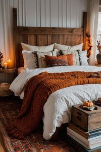 Create a warm and inviting bedroom perfect for fall with a quilt in rich autumn colors, cozy pillows, and a wooden tray with hot cider. Decorate with dried flowers and pumpkin candles for a cozy touch.