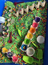 Easter sensory bin I died green rice in 2 different shades of green. Then I colored dried chick peas different colors. I added egg crates with plastic eggs hot glued in so the children color sort chick peas. I used acrylic paint to color rice and chick peas. It's a brighter color and it last longer.