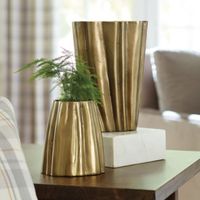 This golden flower vase from designer Suzanne Kasler is really a piece of functional art. 's a great way to add beauty and interest to a spot that's missing that final touch, Suzanne notes. The organic silhouette is sculpted of aluminum and hand finished in burnished gold to accentuate to the flowing lines and scalloped texture. Suzanne Kasler Gold Vase features: Lovely housewarming or hostess gift Gold finish Handmade of aluminum Watertight