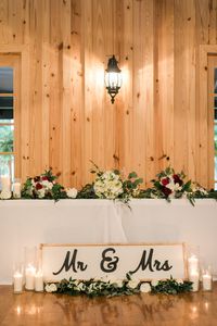 | maroon + white wedding flowers | head table wedding decorations | modern rustic wedding decorations | farmhouse wedding reception decorations | farmhouse wedding head table decor | farmhouse wedding sweetheart table | photo taken at THE SPRINGS Event Venue. follow this pin to our website for more information, or to book your free tour! SPRINGS location: The Ranch in Denton, TX photographer:  Kylie Crump Photography #weddingflowers #weddingreception #farmhousewedding #headtable #sweethearttable