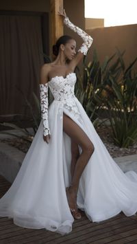 This A-line wedding dress features a sophisticated silhouette with a slit at the skirt and detachable sleeves. The bodice and sleeves are enhanced with romantic lace appliqués that cascade down to the floor. Corset back with lacing and zippers complete the look. This stunning gown is sure to make your special day truly unforgettable.