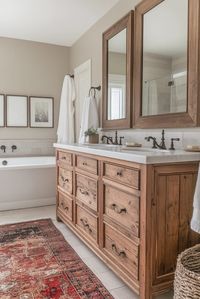 The Antique Modern Charm in a vintage modern master bath pairs antique pieces with modern minimalist fixtures. Vintage mirrors and vanities complement sleek taps and create a unique blend of eras. Click here for more antique modern bathroom ideas.