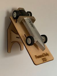 Laser cut Pinewood Derby Car Display. Can be mounted directly to the wall as a shelf or positioned two ways as a stand to show off your Derby car. Display can be personalized by including the text/font you want cut into it. If this option is not chosen, the Display will be cut as shown. It will ship unassembled and is very easy to put together. Though the fit is snug, it is recommended to glue it to ensure it stays together. For bulk quantities, please contact me. Assembly: Insert Item 2 into bo