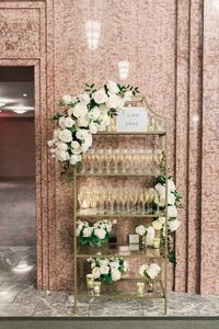 Guests were welcomed with glasses of champagne letting them know where to find their seats displayed on a gold shelf embellished with white florals.