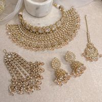 Antique Gold polished small choker and large necklace set made up of of clear zircon crystals , light Golden crystal beads with off white pearl drops Comes complete with matching tikka:  2 inch pendant with 4 inch chain, and jhumka earrings measuring 2.5 inch in length. Jhumar is optional  This set is ready to ship as seen with gift box.